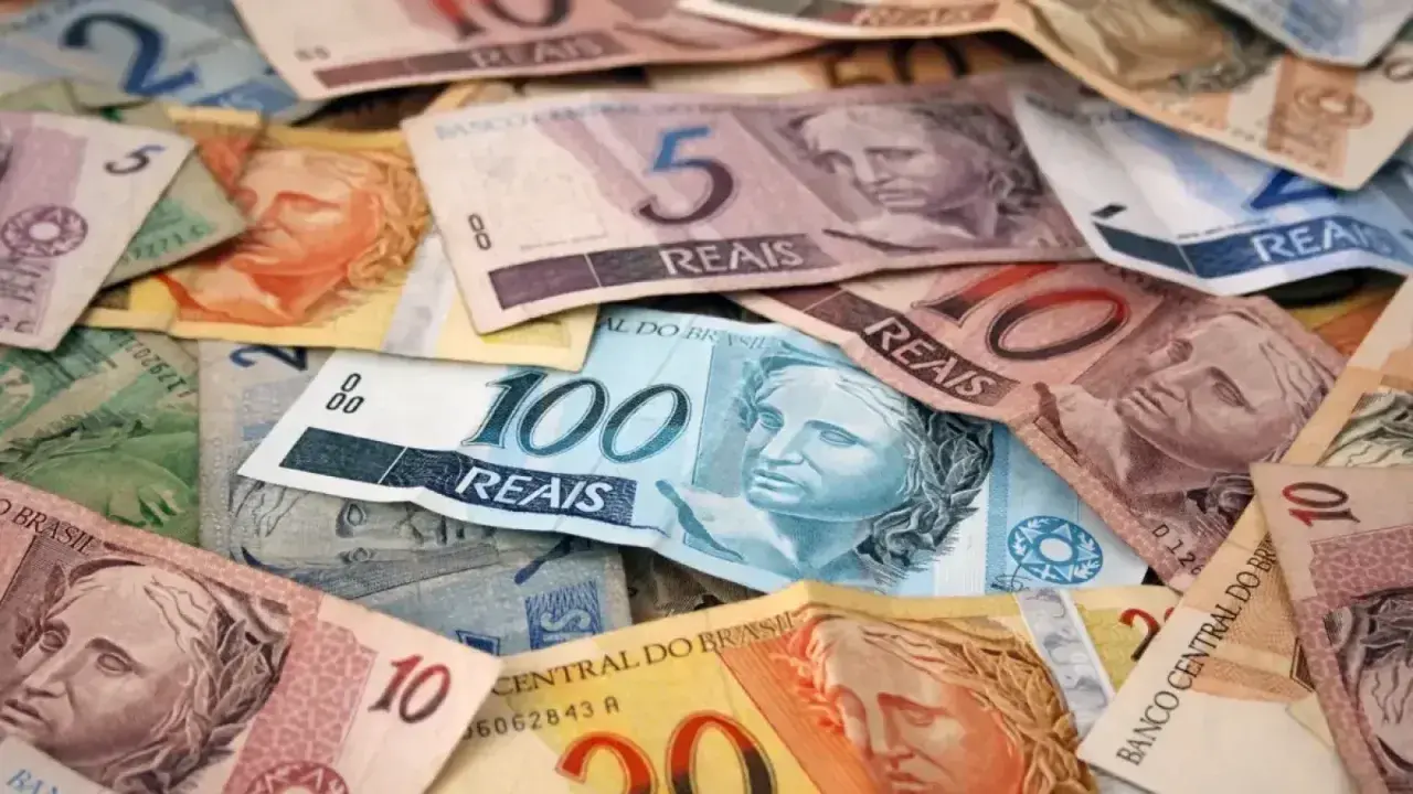 Stosy banknotów, w tym 100, 10 i 5 reali, stanowią walutę Brazylii.