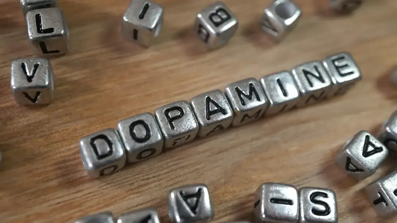 Cubos plateados forman la palabra "DOPAMINE". Descubre cómo aumentar tu dopamina para sentirte mejor.