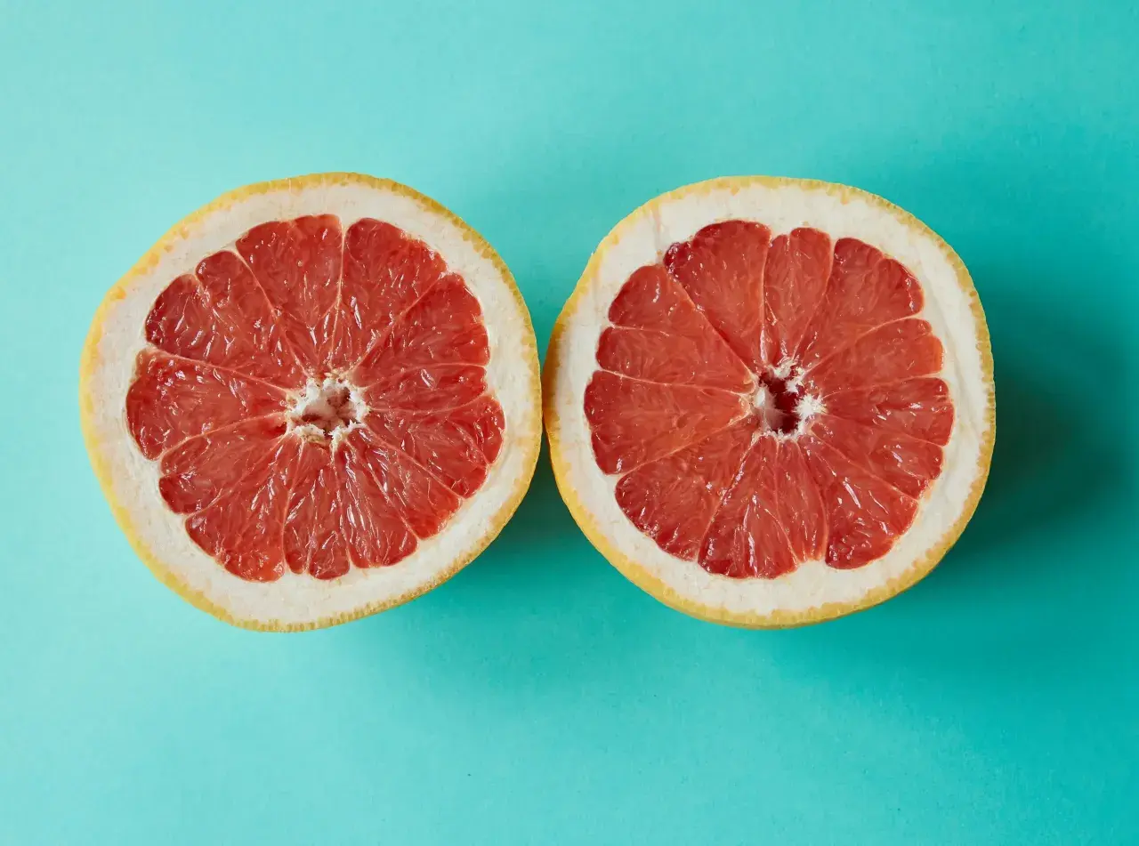 Zwei Hälften einer Grapefruit auf türkisfarbenem Hintergrund. Grapefruit ist ein Obst, in dem viel Calcium ist.