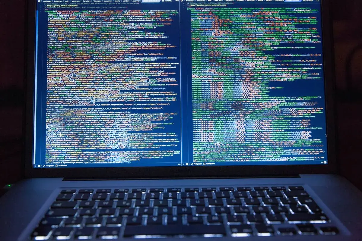 Programista pracuje nad kodem. Na ekranie laptopa widać wiele linii kodu, co pokazuje, co robi programista.