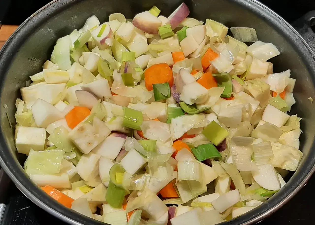 Poêlée de légumes coupés en dés, prêts pour un savoureux bouillon de légume. Carottes, poireaux et navets se mélangent.