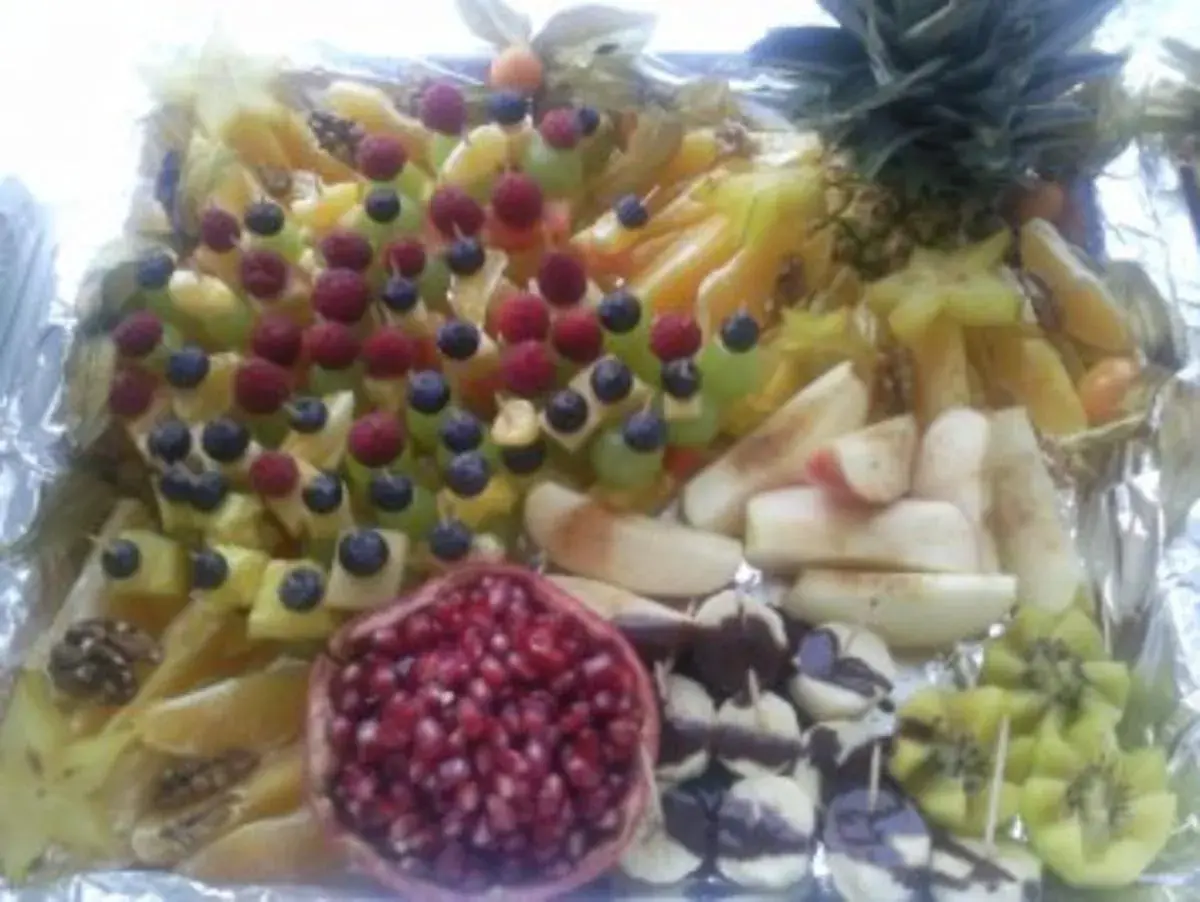 Eine bunte, einfach zubereitete obstplatte mit Ananas, Sternfrucht, Beeren, Granatapfel und Kiwi.