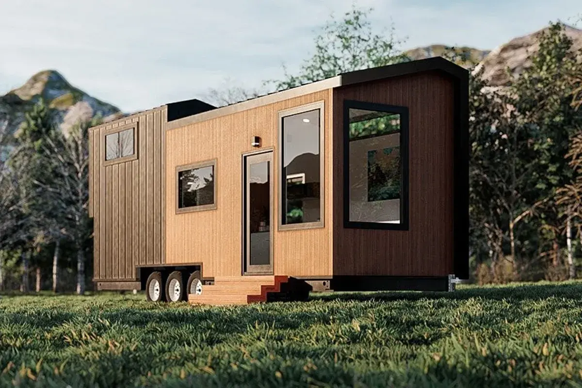 Tiny house sur roues dans un paysage verdoyant. La question "un particulier peut il acheter une maison en zone agricole" se pose face à ce type d'habitat.