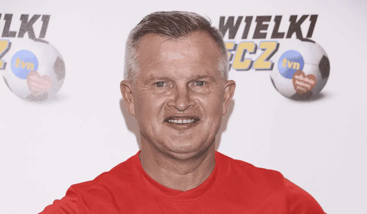 Uśmiechnięty bieleninik z TVN w czerwonej koszulce, na tle piłki nożnej z logo WOŚP.