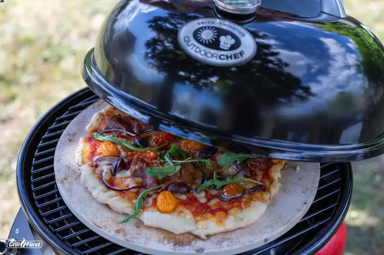 Selbstgemachte Pizza auf einem Pizzastein im Outdoorchef Grill. Die Frage ist nur, wieviel Grad im Ofen für den perfekten Biss?