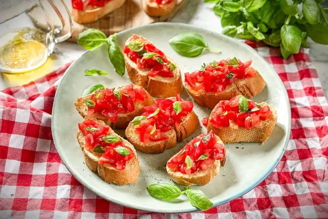Frische italienische Crostini mit Tomaten und Basilikum auf einem Teller, garniert mit frischen Basilikumblättern.