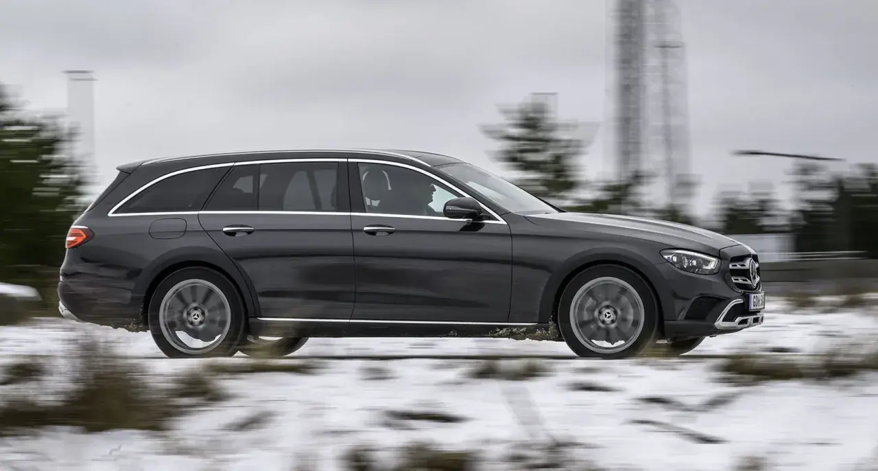 Mörkgrå Mercedes All-Terrain wagon kör på en snöig väg, redo för alla utmaningar.