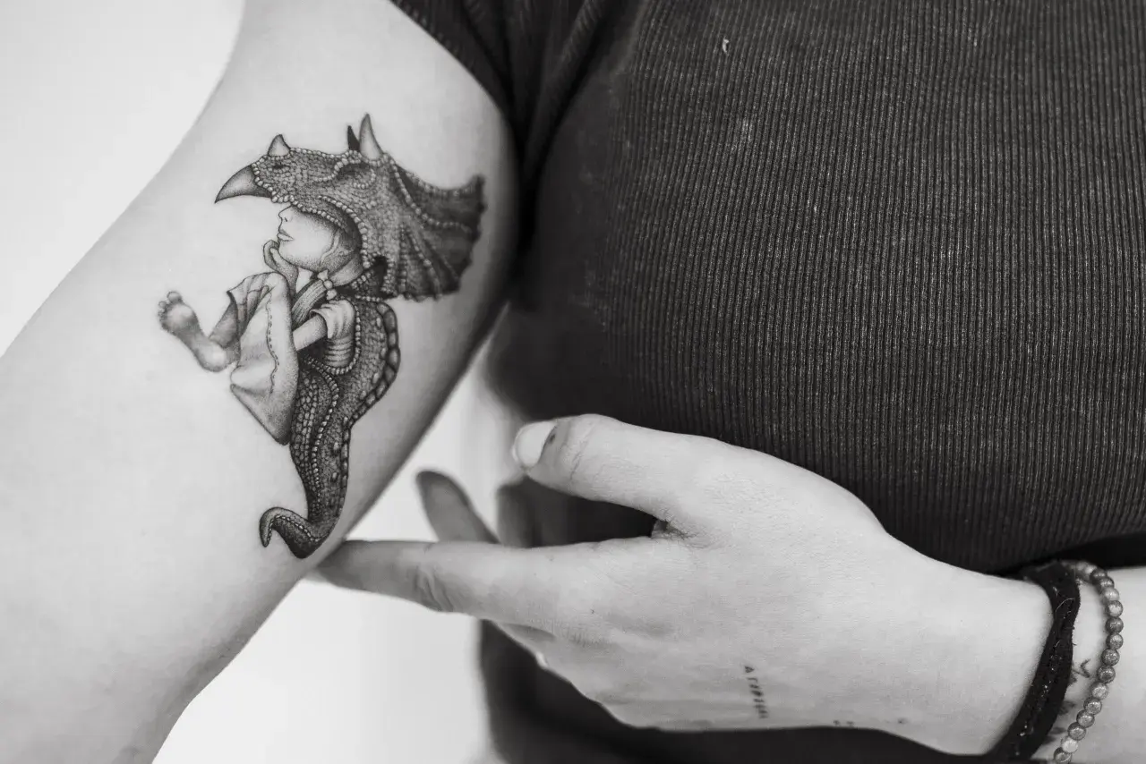 Un tatuaje de un niño con un casco de dinosaurio, con detalles intrincados, que evoca la magia de los tatuajes sevillanos.