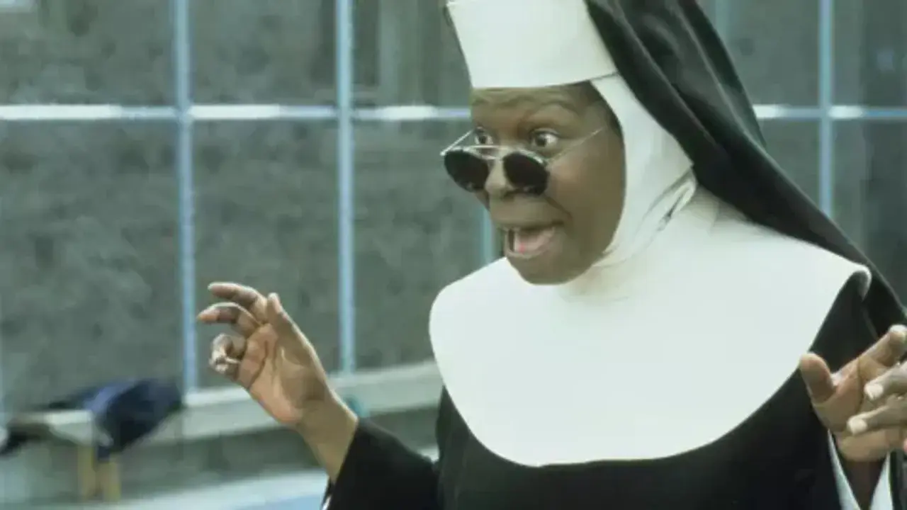 Whoopi Goldberg w roli siostry w filmie "Zakonnica w przebraniu 2: Powrót do habitu" z okularami i w rozbawionej pozie.