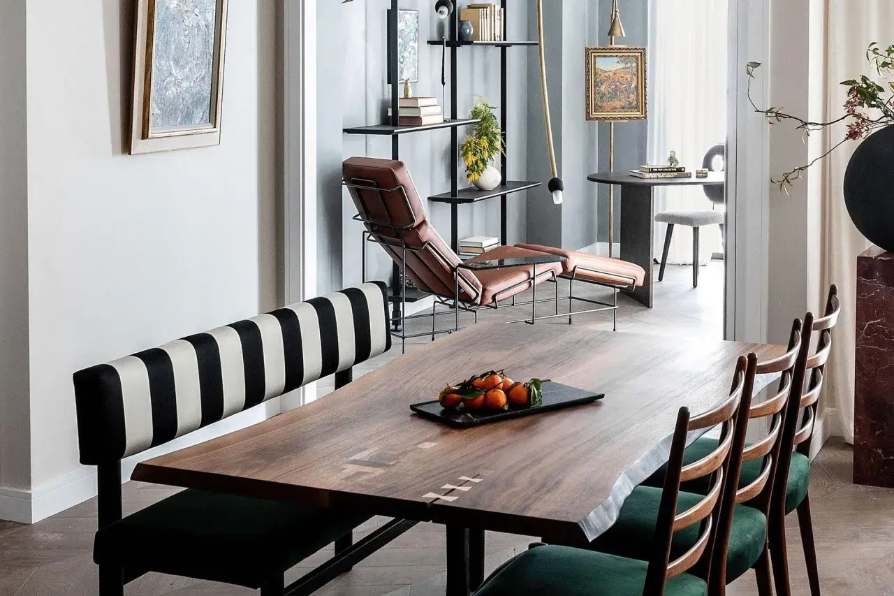 A large, live-edge wooden table with inlaid details, showcasing its impressive table dimension, is set with a tray of tangerines.