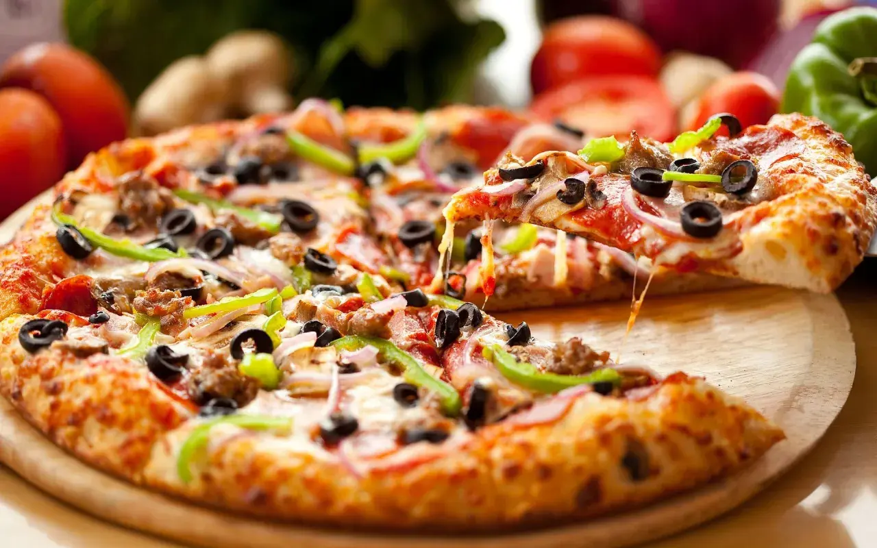 Idealny dzień pizzy! Gorąca, ciągnąca się pizza z mnóstwem dodatków: oliwkami, papryką, cebulą i mięsem.