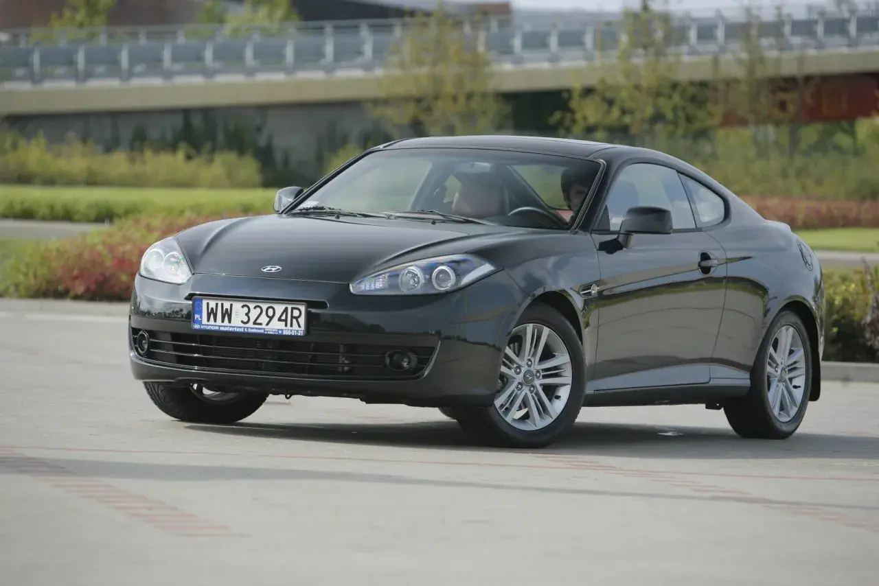 Ciemnoszary Hyundai Coupe 2.7 V6 z brązową tapicerką, zaparkowany na zewnątrz.