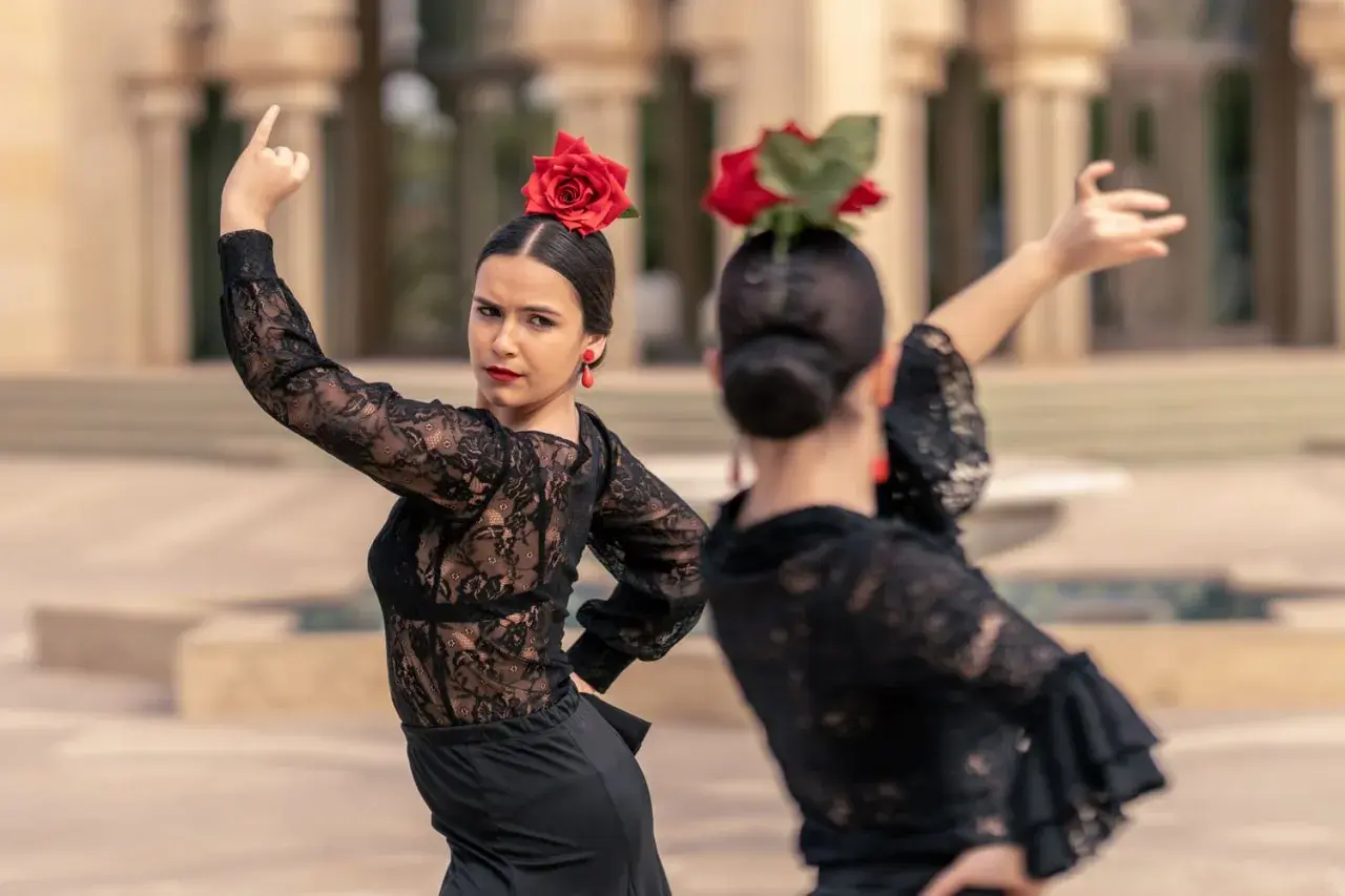 Una sevillana flamenca, con rosa roja en el pelo y pendientes a juego, baila con pasión.