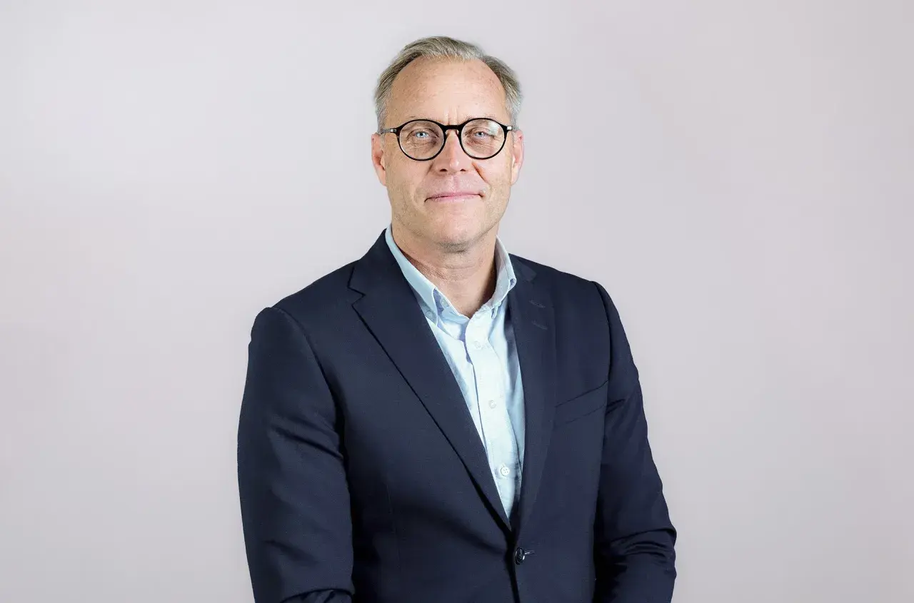 Ahlsell VD, en man med glasögon i mörkblå kavaj och ljusblå skjorta, ler mot kameran.
