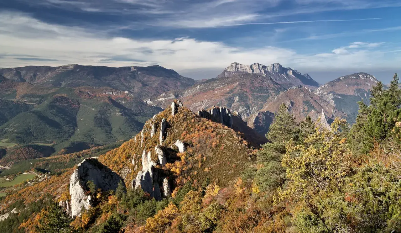 Vue panoramique des gorges de la Roanne en automne. Un sentier de randonnée serpente à travers des crêtes rocheuses et des forêts aux couleurs flamboyantes.