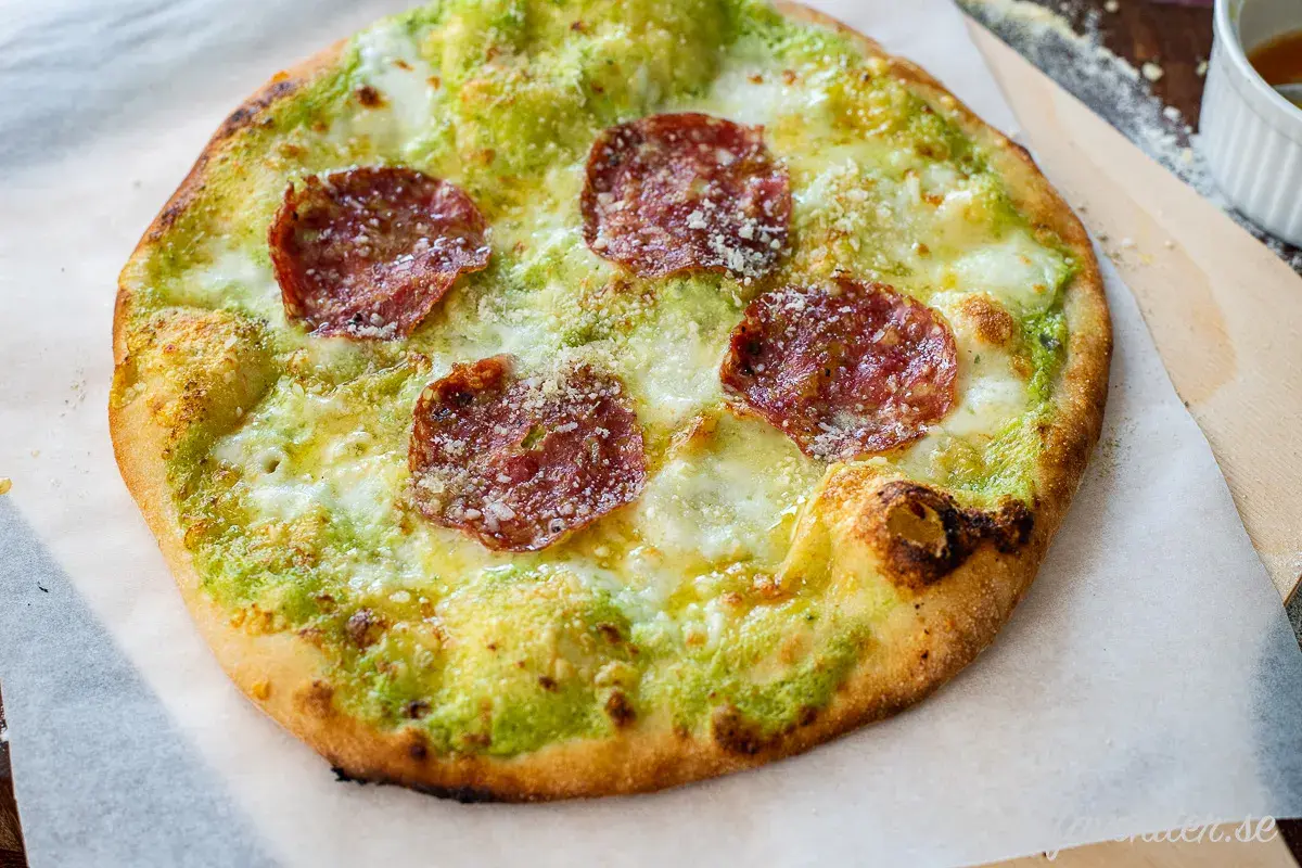 En pizza bianco med salami, ost och grön sås.