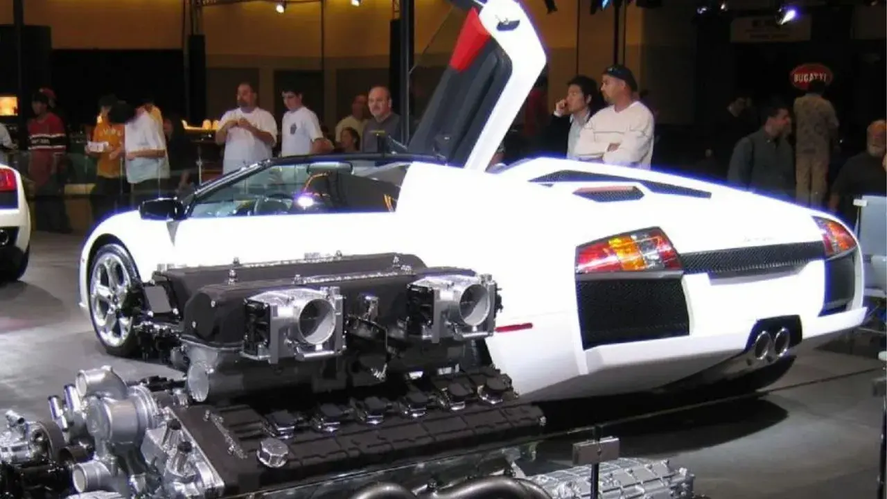Biały Lamborghini Murcielago z otwartymi drzwiami i wyeksponowanym potężnym silnikiem V12.
