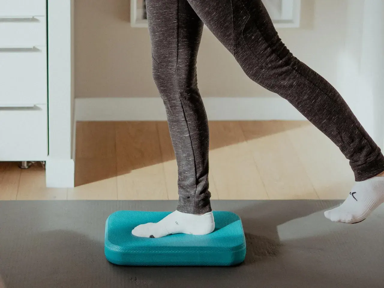 Exercice d'équilibre sur un coussin bleu pour améliorer la proprioception cheville.