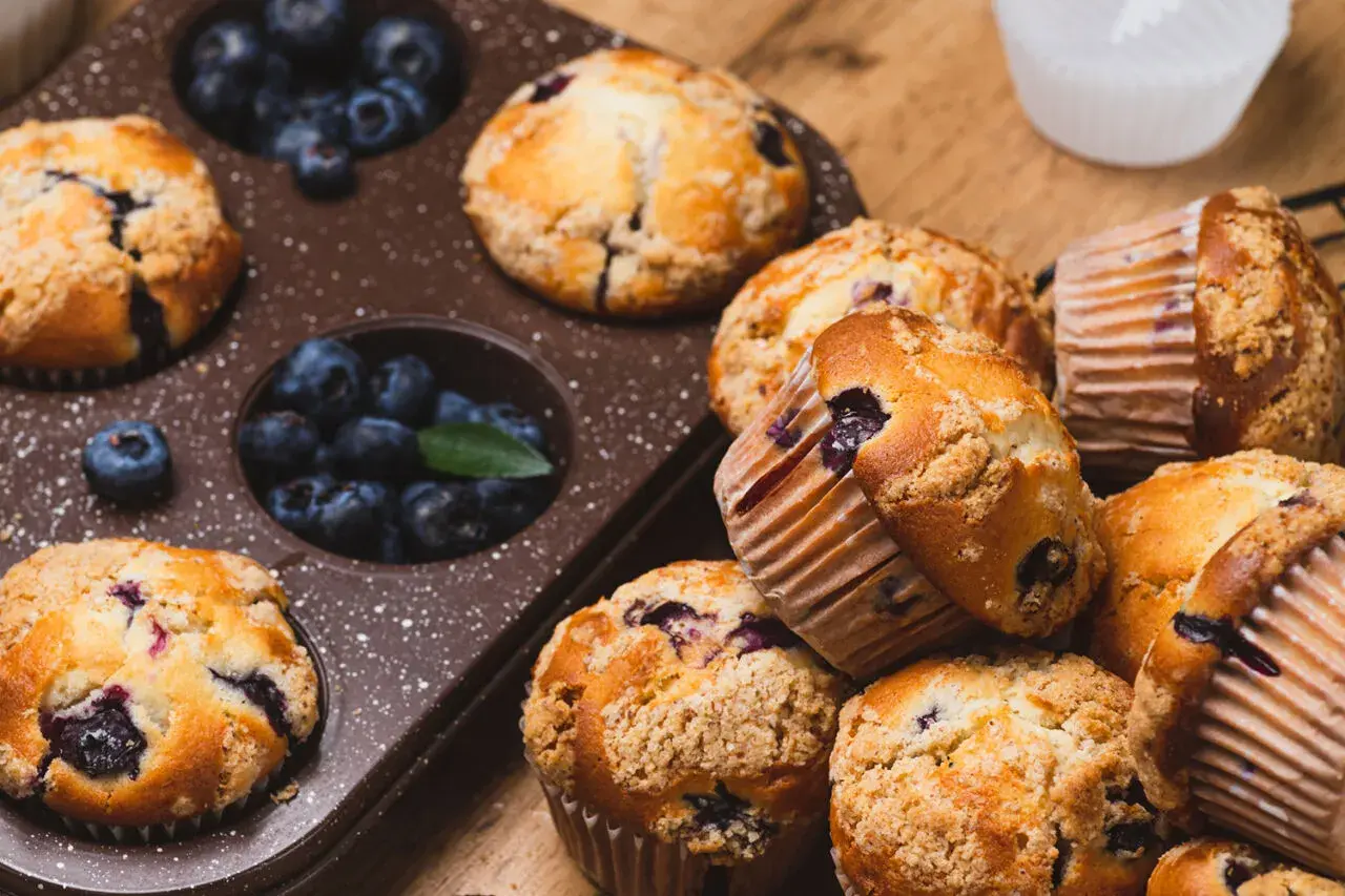 Pyszne muffinki z jagodami, niektóre w foremce, inne ułożone na desce. Ile piec muffinki?
