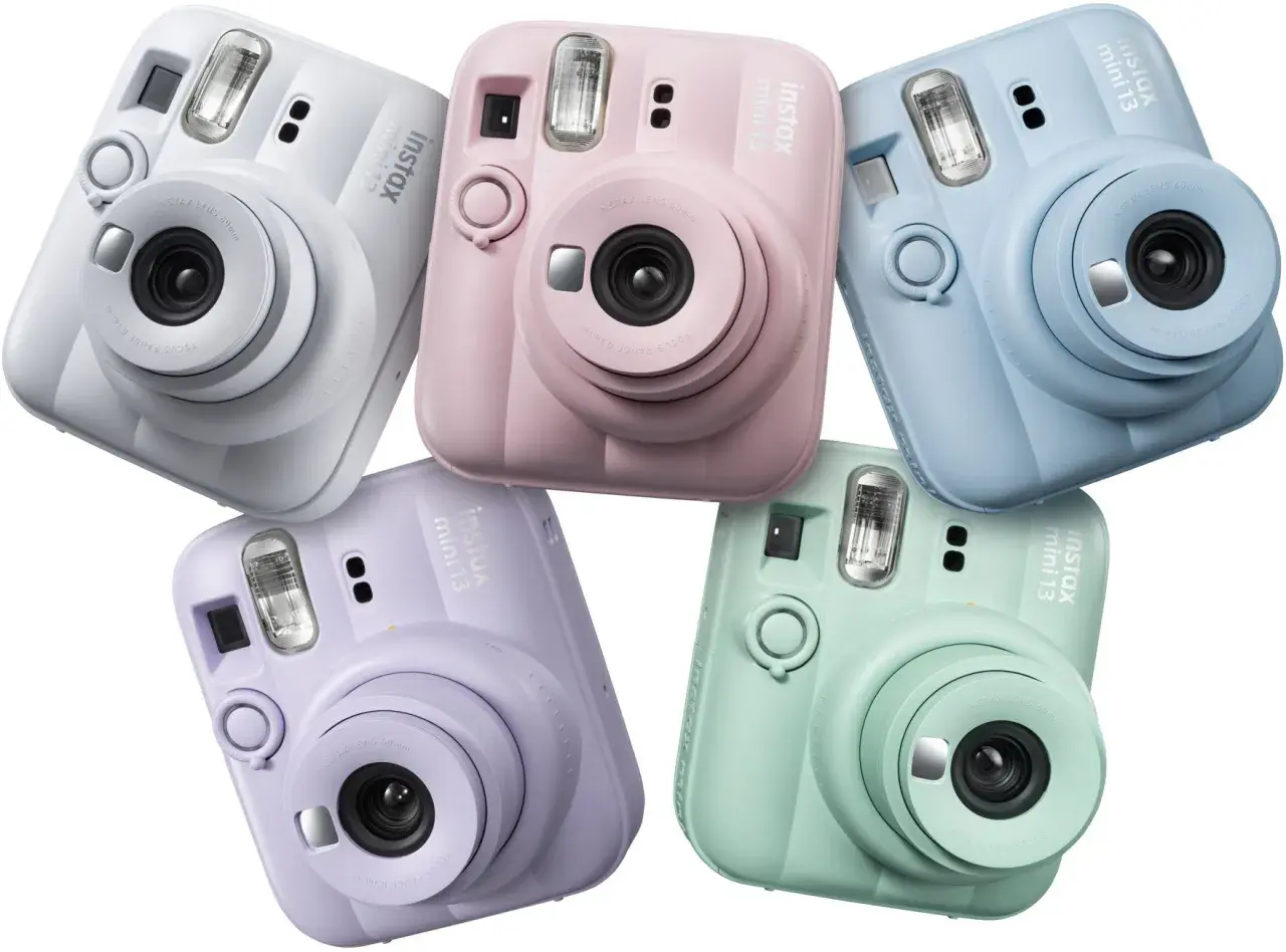 Pięć aparatów Instax Mini 13 w pastelowych kolorach: białym, różowym, niebieskim, fioletowym i miętowym.