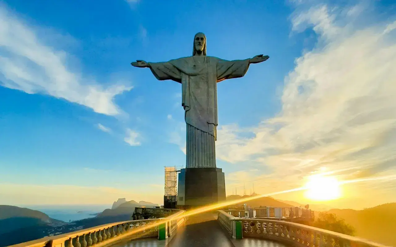 Christusstatue in Brasilien mit weit ausgebreiteten Armen, die den Sonnenuntergang über Rio de Janeiro überblickt.