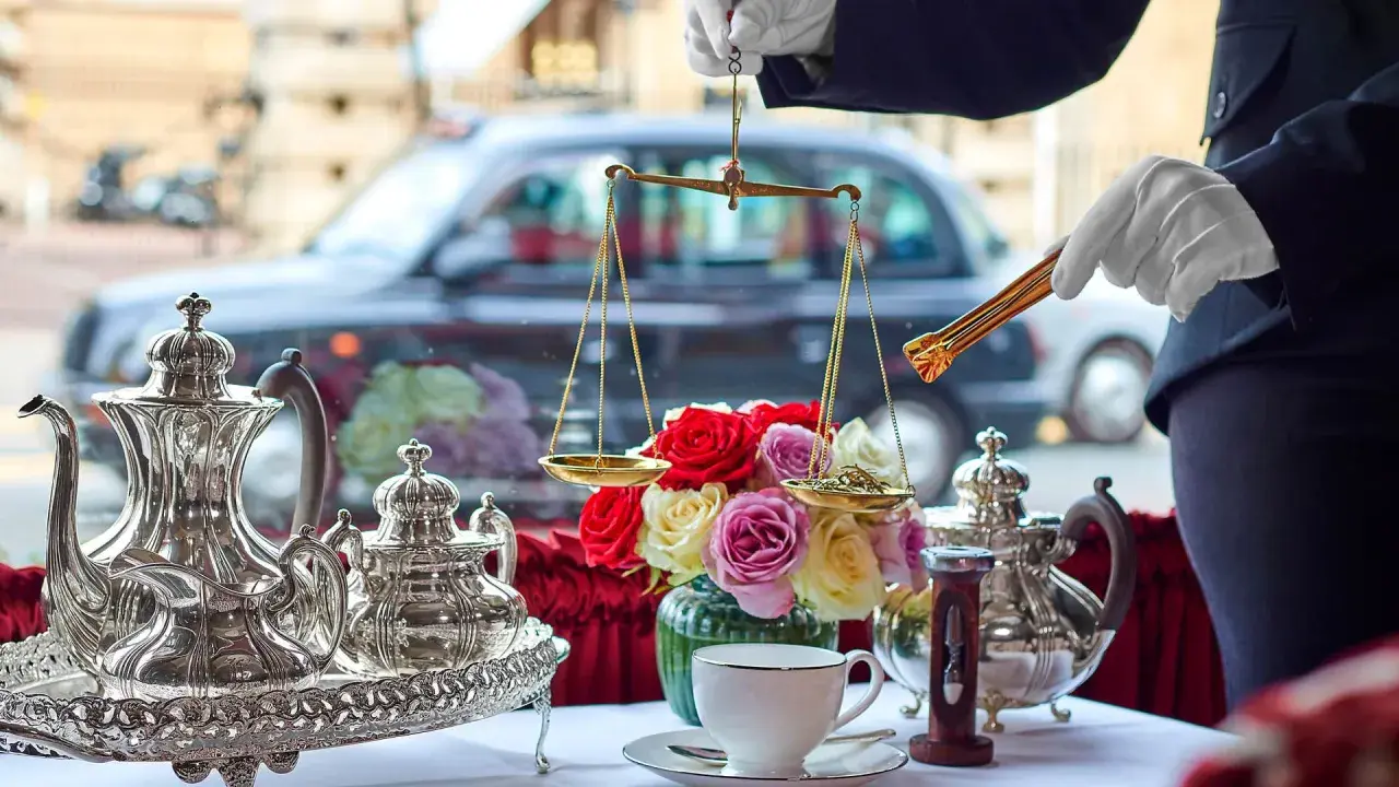 En elegant uppsättning för klassisk afternoon tea med silverkannor, en blomsterbukett och en våg för att mäta teblad.