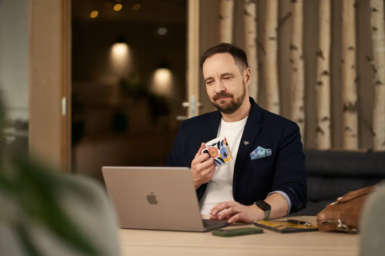 Man med kaffemugg vid laptop, funderar på firmabil regler.