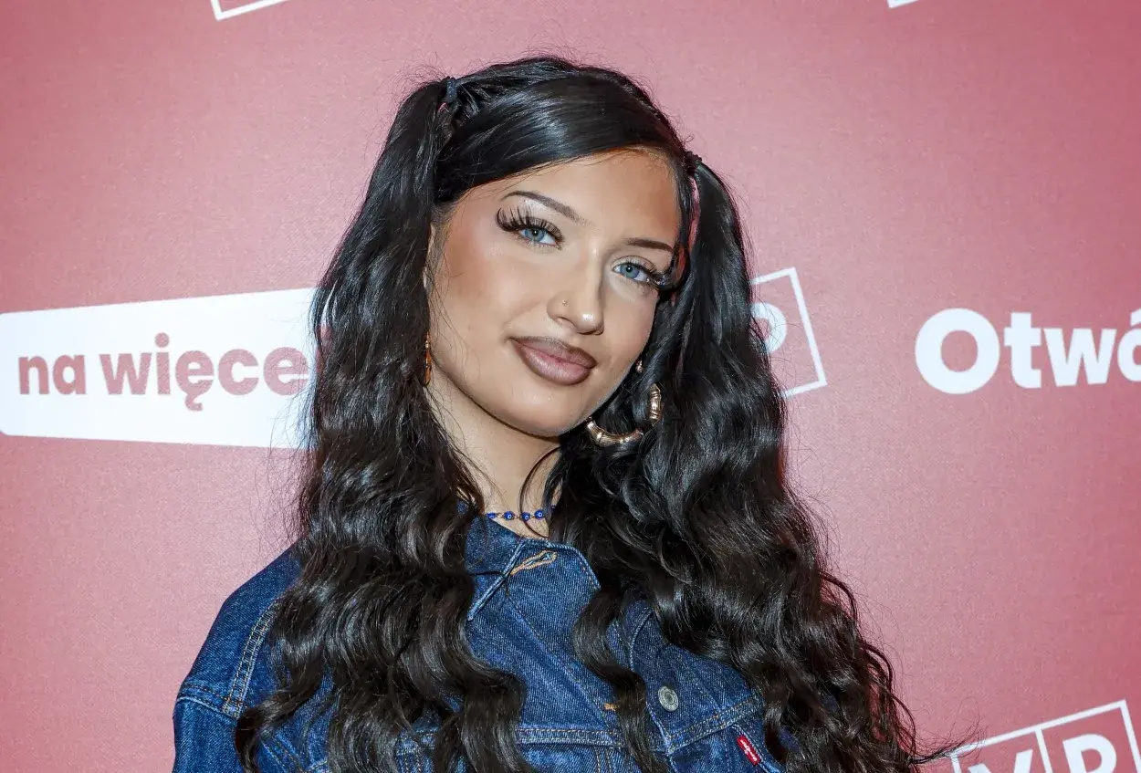 Młoda Viki Gabor, z charakterystycznymi kucykami i w dżinsowej kurtce, pozuje na ściance. Jej wiek to tajemnica, ale talent jest oczywisty.