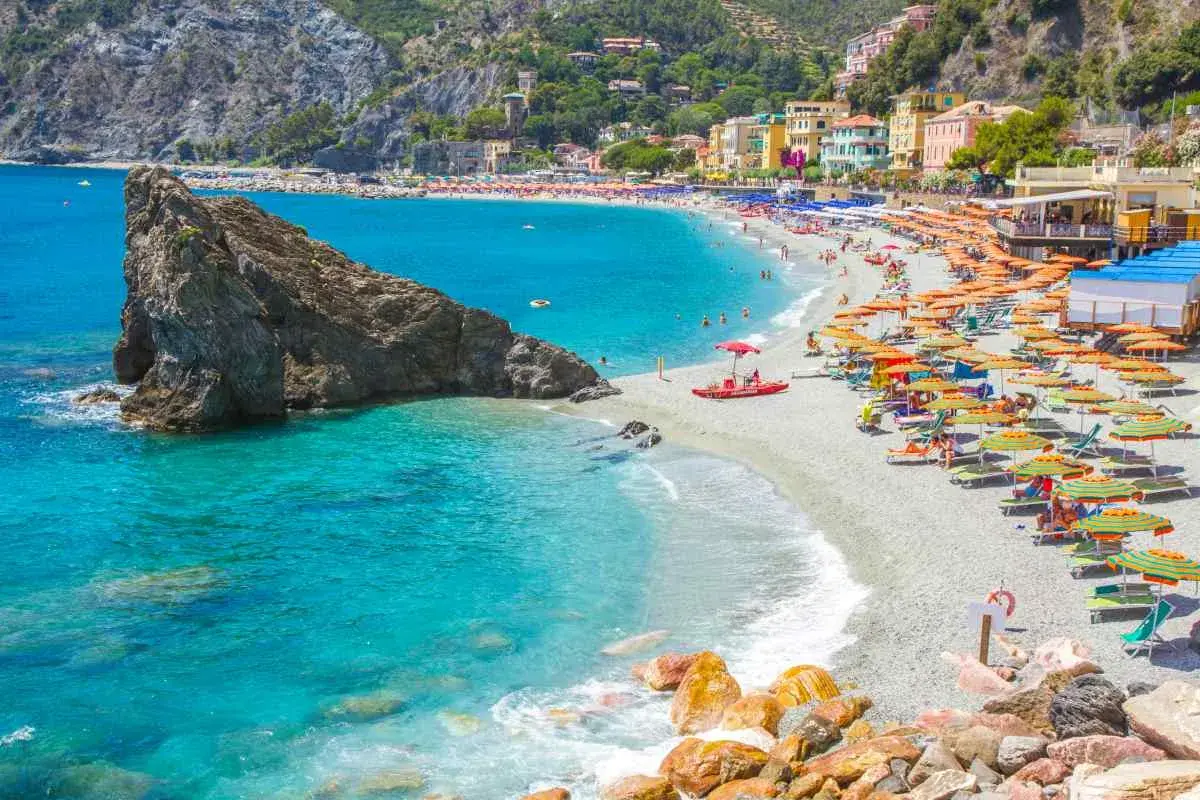 La monterosso spiaggia libera è affollata di ombrelloni colorati e bagnanti che si godono il sole e il mare cristallino.
