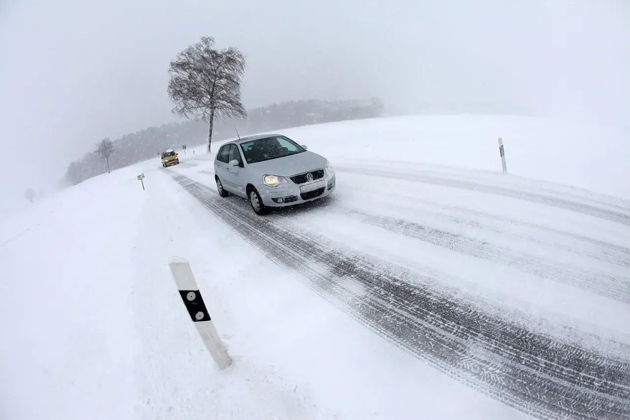 Coches circulando por carreteras con nieve en un día de invierno con poca visibilidad.