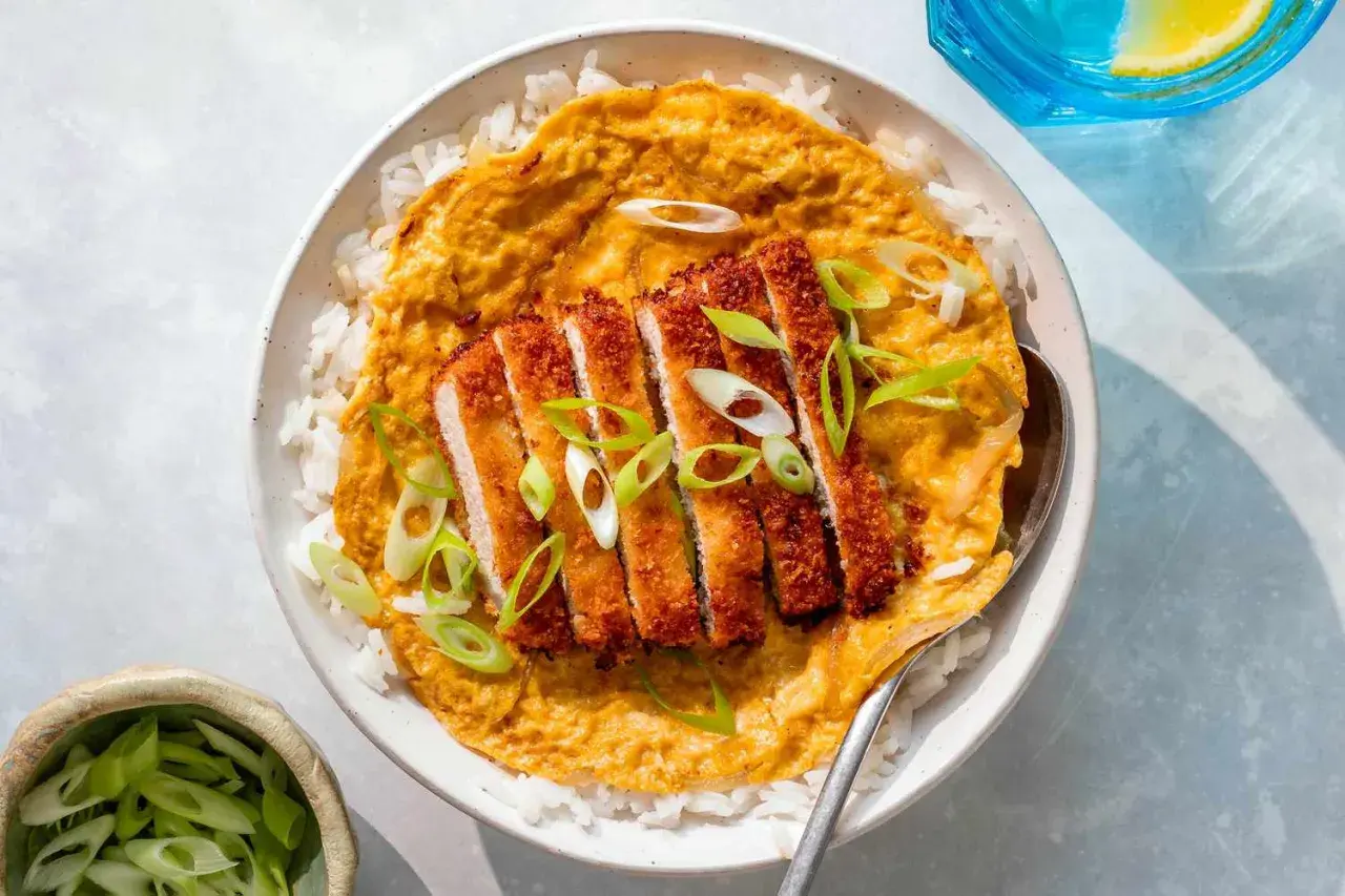 A delicious katsu don with crispy pork cutlet over rice, topped with a savory egg mixture and garnished with fresh scallions.