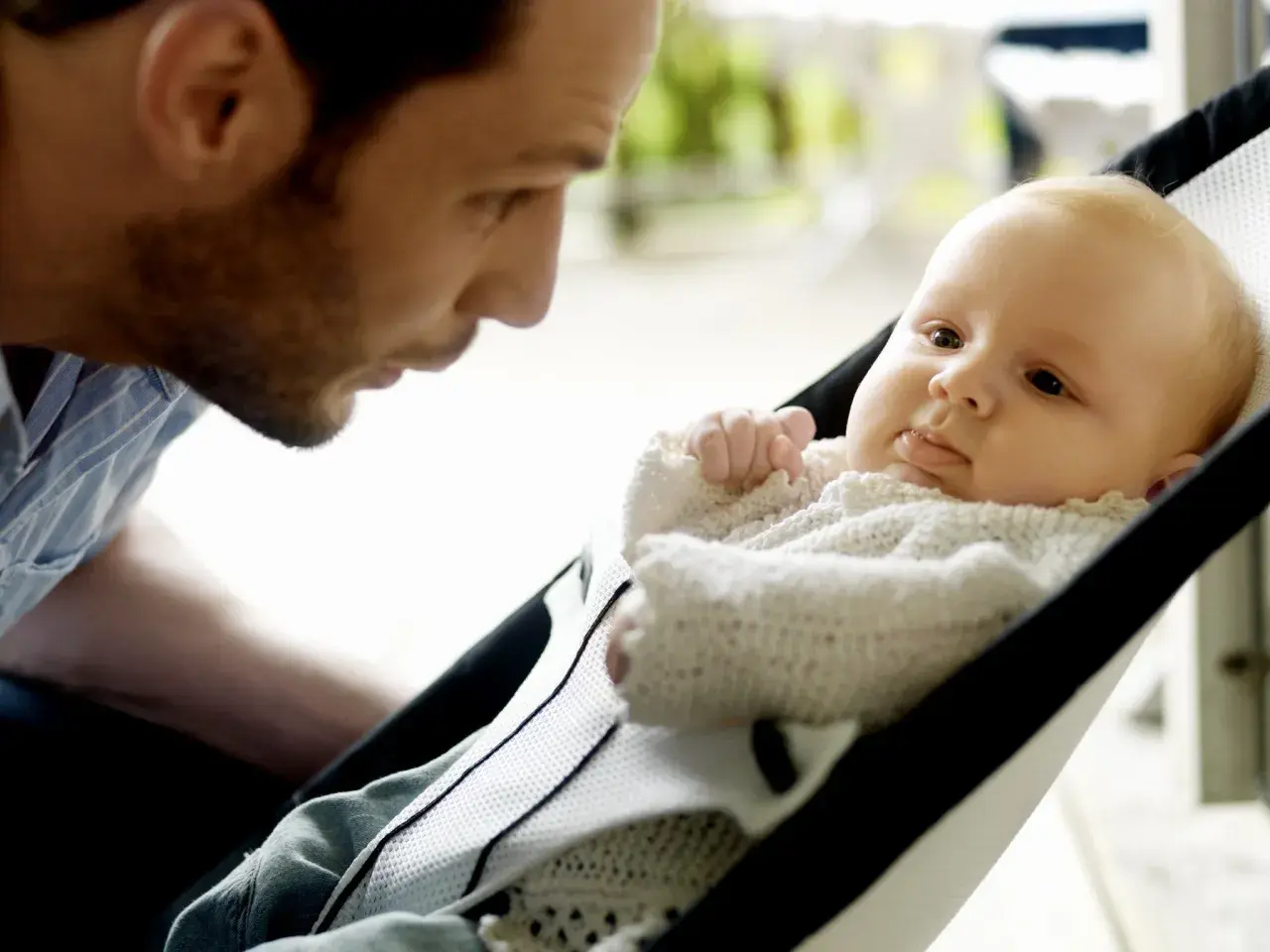 Pappa tittar kärleksfullt på sin bebis i en BabyBjörn babysitter.
