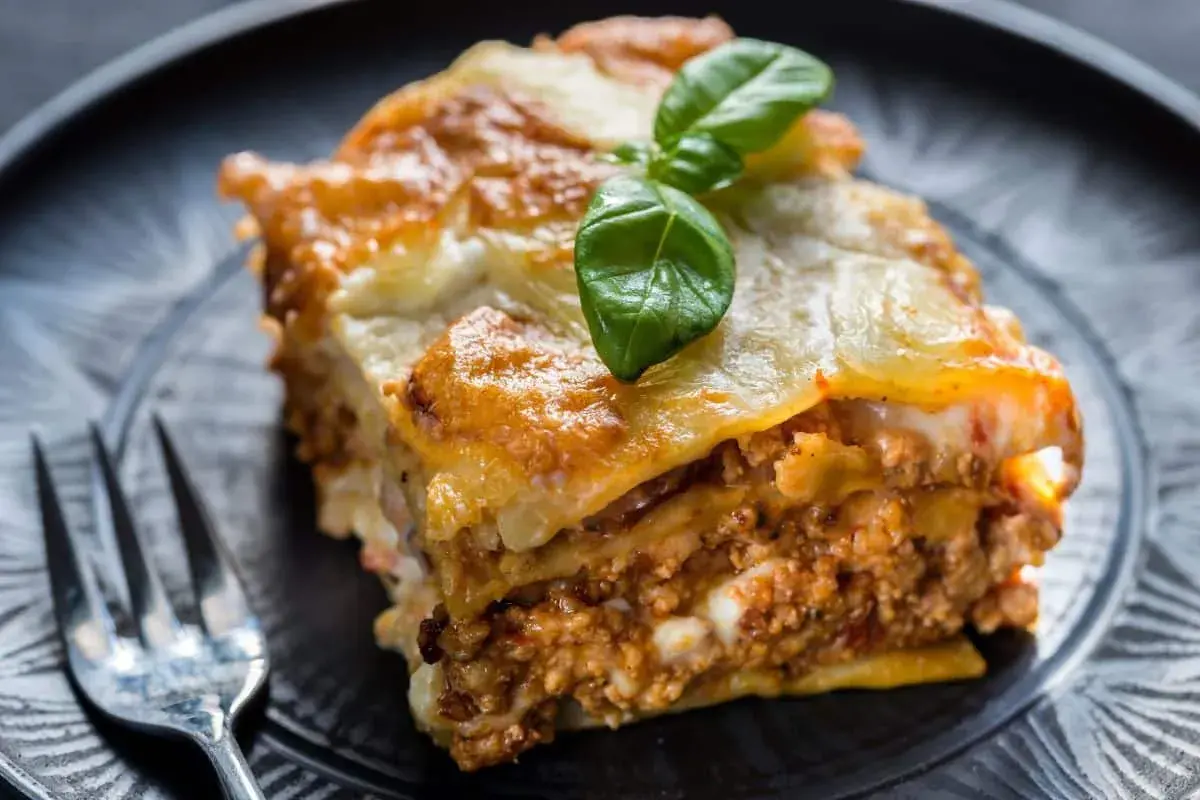Une part de lasagne maison, dorée et gratinée, garnie de viande et de béchamel. Parfaite pour une recette lasagne réussie.