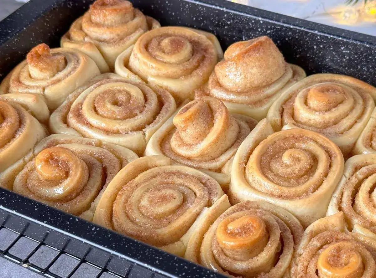 Frisch gebackene, gesunde Zimtschnecken in einer Backform. Sie duften nach Zimt und Zucker und sind bereit zum Genießen.