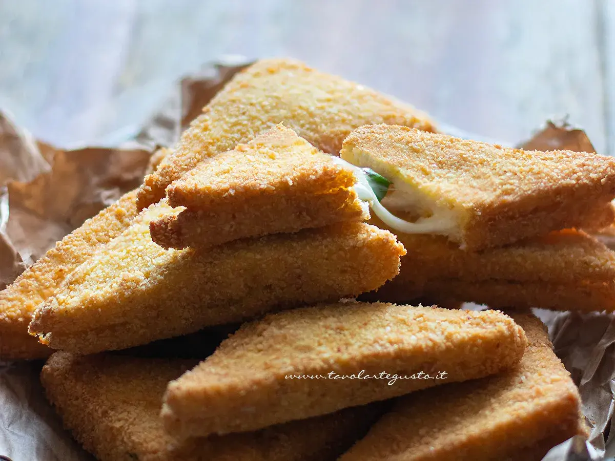 Triangoli dorati di formaggio in carrozza, con il formaggio filante che fuoriesce da uno.