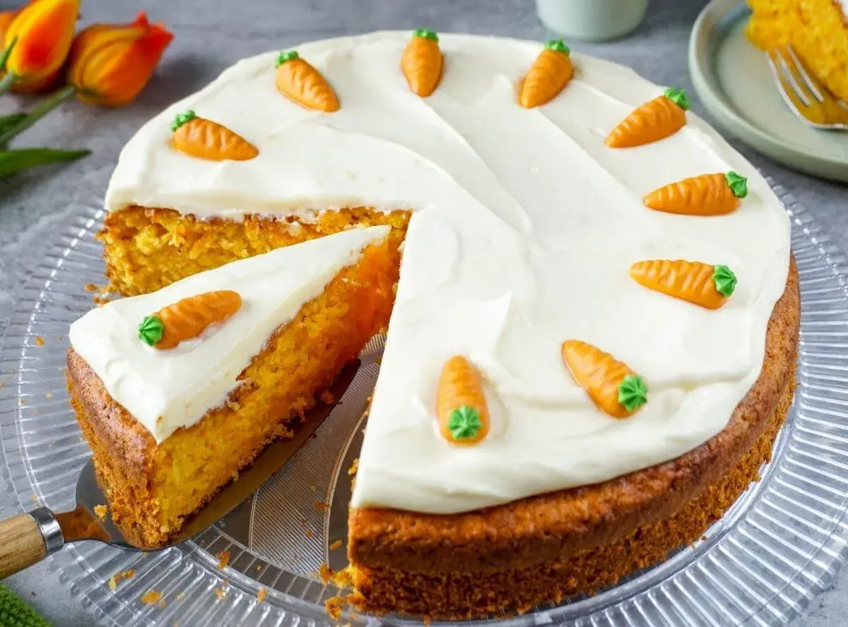 Ein saftiger Karottenkuchen mit weißem Zuckerguss und kleinen Marzipanmöhren, perfekt als Geburtstagskuchen für Kinder.