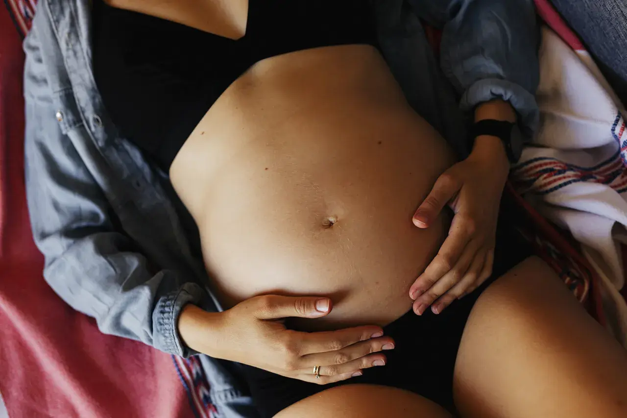 Ciężarna kobieta obejmuje brzuch. Może odczuwać ból pachwin w ciąży, ale skupia się na swoim maleństwie.