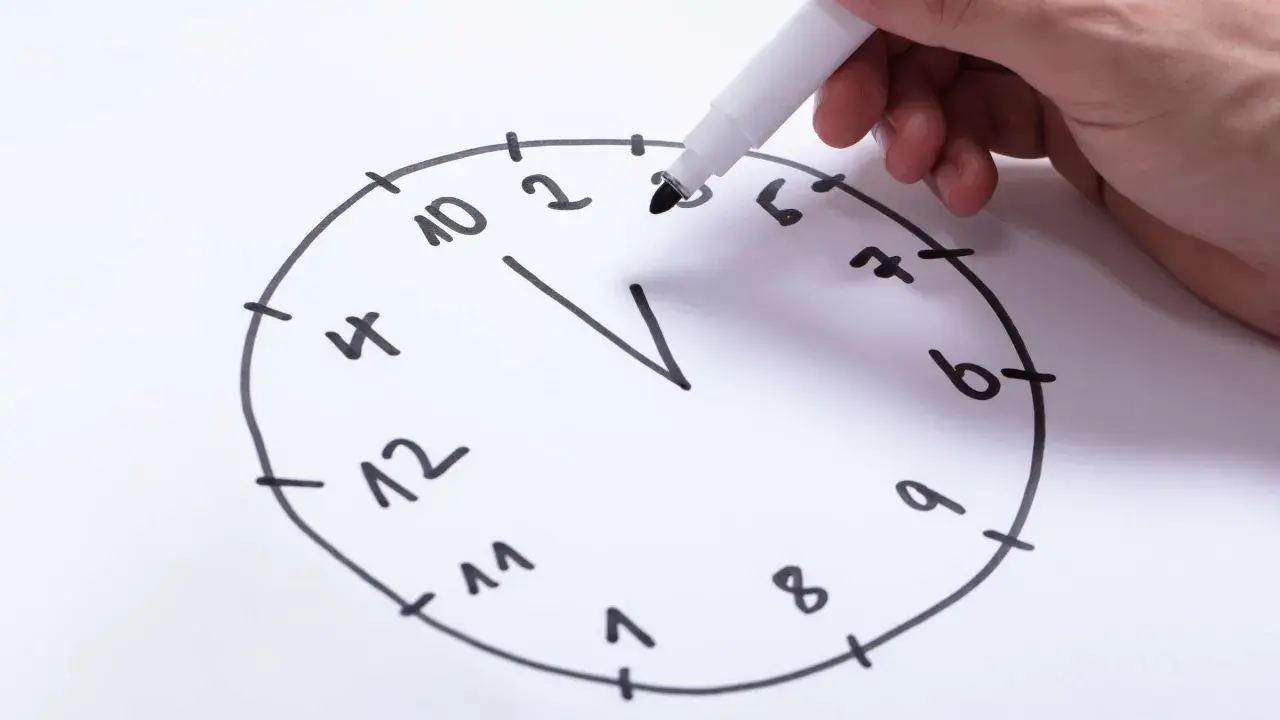 Hand zeichnet eine Uhr für einen Uhrentest Demenz. Die Zahlen sind unvollständig und die Zeiger fehlen.