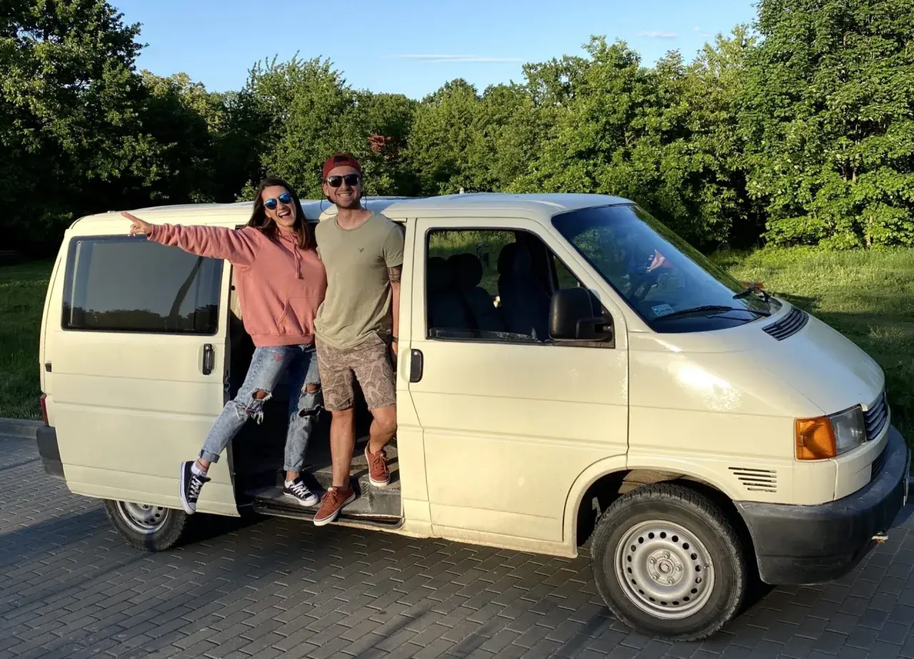 Para młoda pozuje przy swoim t4 camperze, gotowa na przygodę.