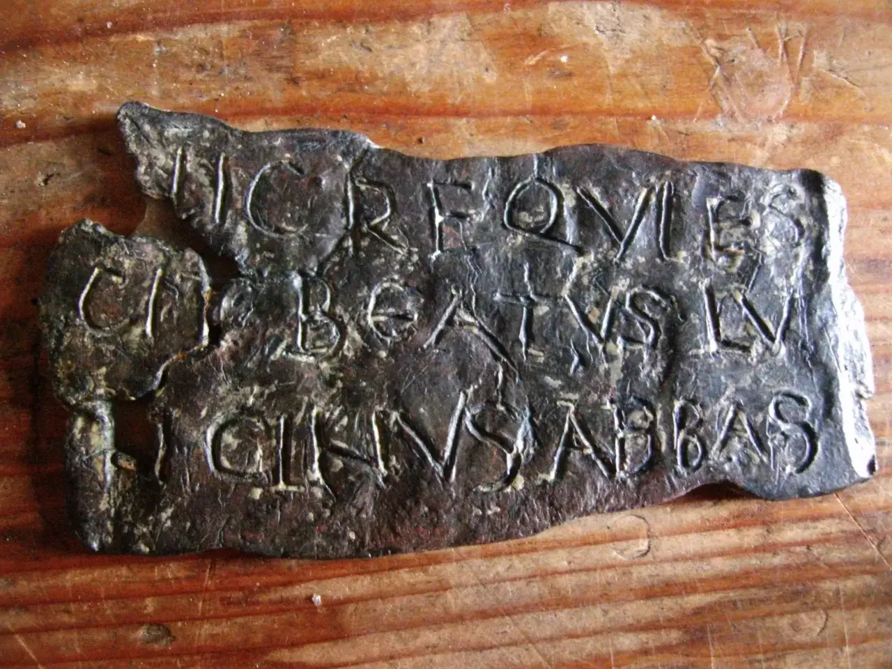 Plaque de métal gravée de lettres latines, possiblement une inscription trouvée près de la tour de Saint-Lupicin.
