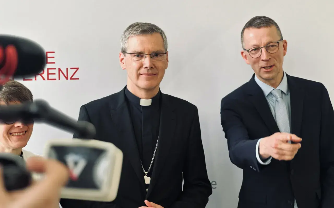 Der Vorsitzende der Deutschen Bischofskonferenz, Georg Bätzing, im Gespräch mit einem Mann im Anzug.