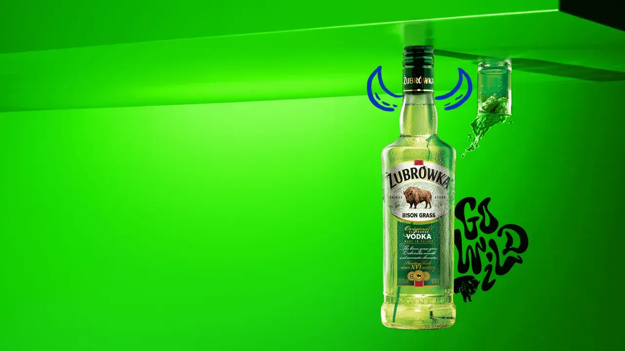 Butelka Żubrówki z trawą żubrową, 37,5% alkoholu. Obok kieliszek z zielonym płynem i napis "Go Wild".