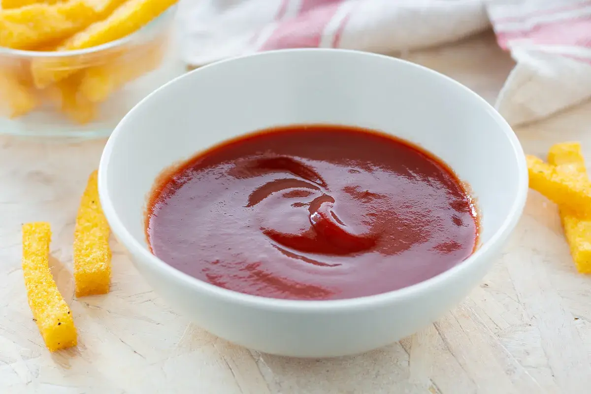 Ciotola di ketchup fatto in casa, con bastoncini di polenta fritta intorno.
