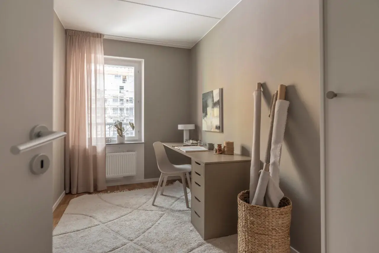 En ljus och inspirerande arbetsplats kontor med skrivbord, stol, textilier och konst.