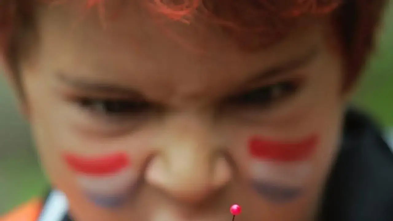 Niño con pintura facial de bandera, con mirada intensa, como si temiera el mal de ojo.