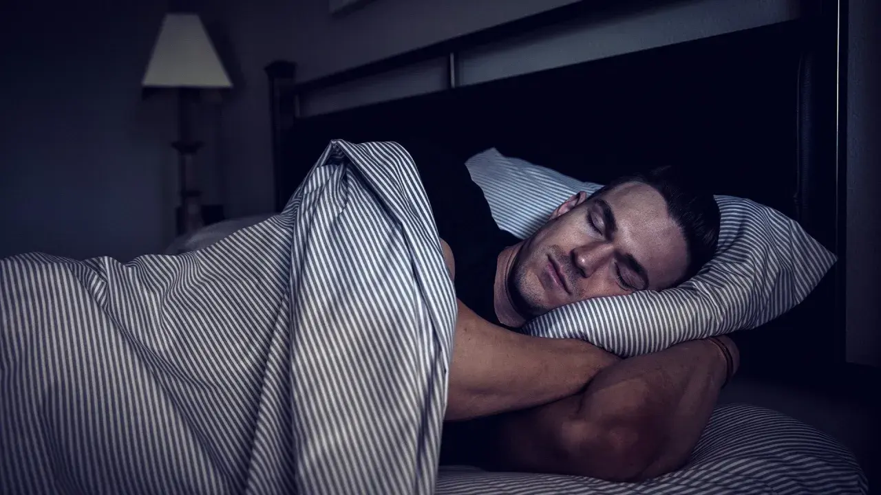 Man sleeping soundly, embracing deep sleep for optimal muscle recovery.