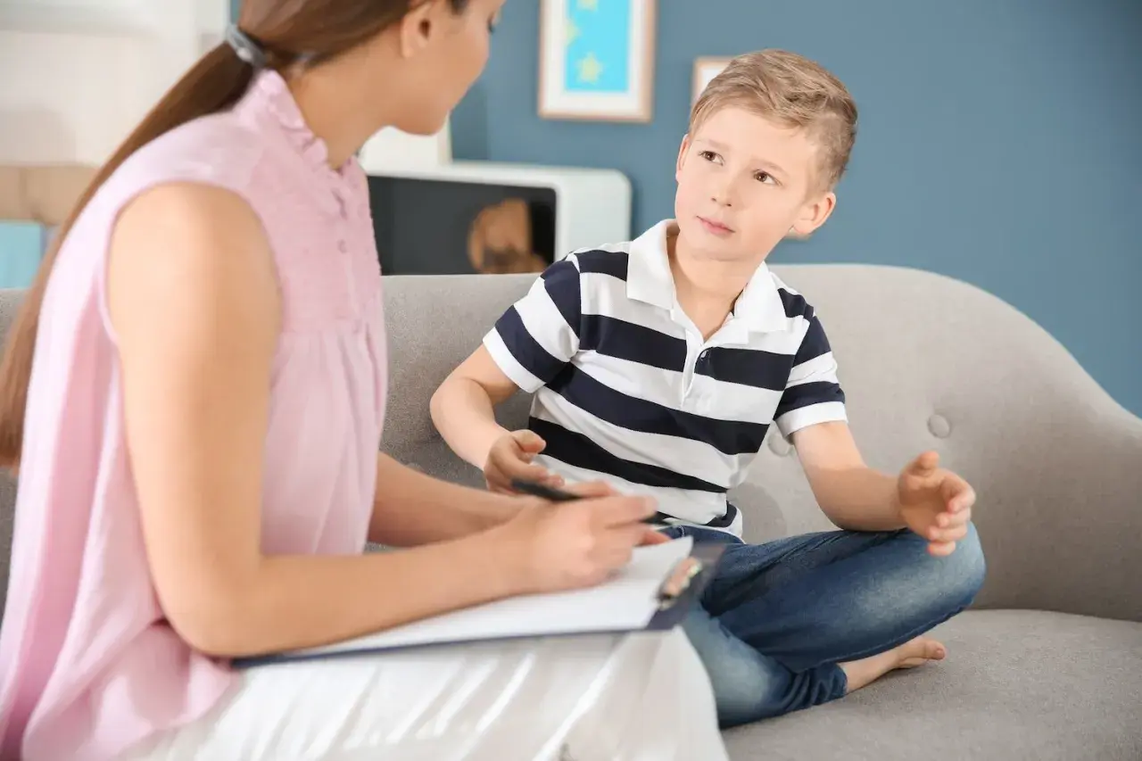 Psycholog rozmawia z chłopcem siedzącym na kanapie.