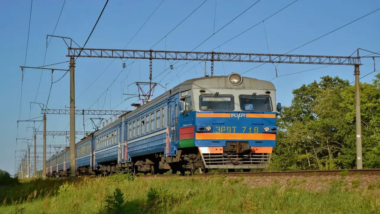 Pociąg elektryczny jedzie po torach, a nad nim widać sieć trakcyjną. To idealny sposób, jak dojechać pociągiem do Kamienia Pomorskiego.