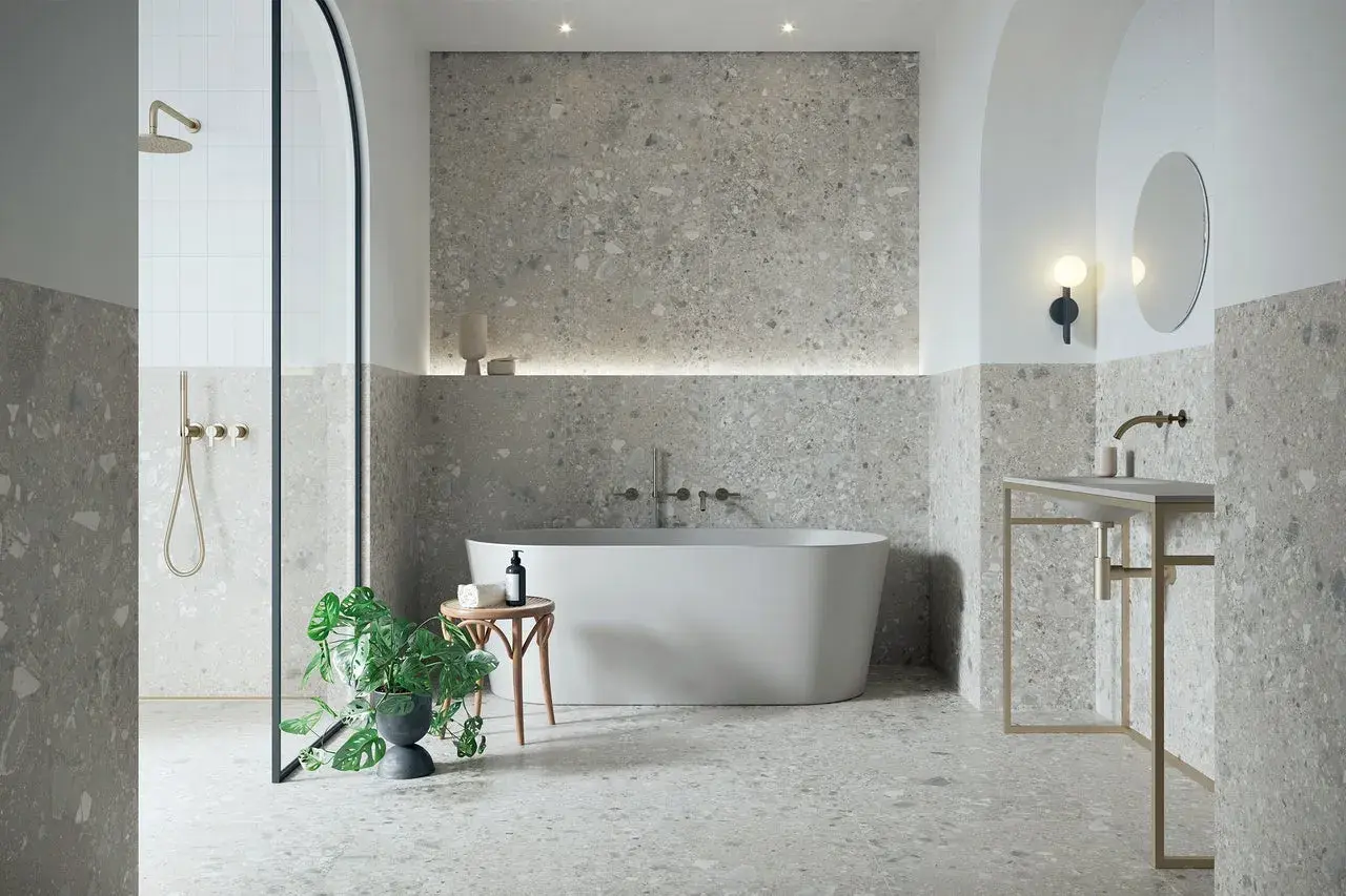 Modernes Badezimmer mit Terrazzo-Fliesen. Der Fliesentrend für Bäder zeigt sich hier in stilvoller Optik mit freistehender Wanne und Dusche.