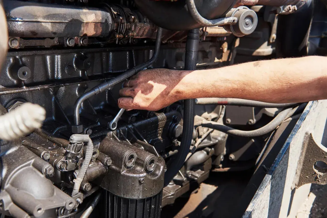 Mano che lavora su un motore, forse per riparare l'alternatore auto.
